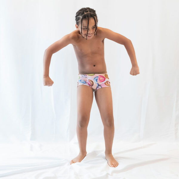 boy posing in boxer style underwear with donuts on them on a white backdrop.